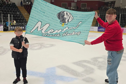 Two people holding a banner with a logo and text on an ice rink.